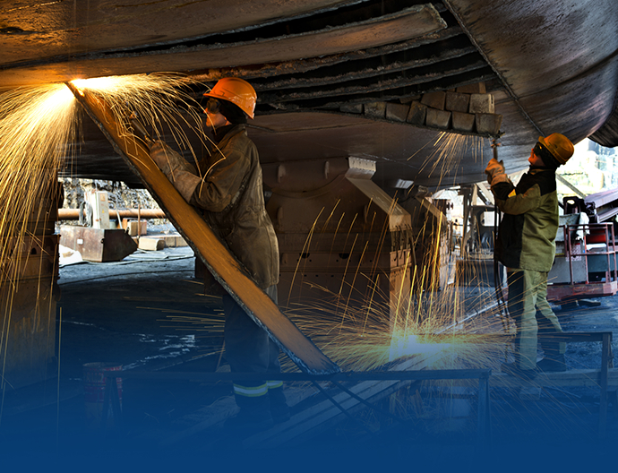 Welders repairing a ship in dry dock