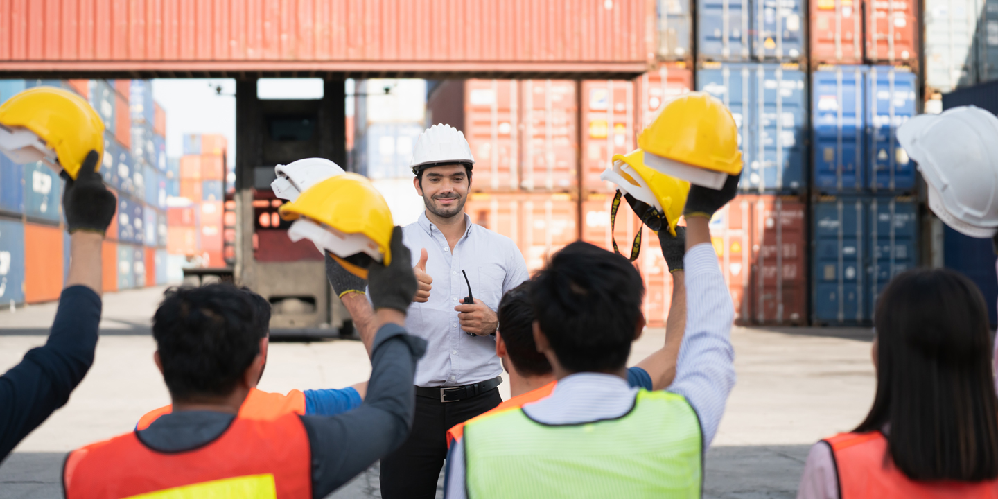 A blue collar worker gives a thumbs up to a coworker